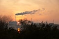 Horizon industry in a small netherland town in Europe, with a big chimney and smoke, sunset and sun as background