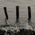 Horizon over water with three wooden stakes and water splash