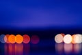 Horizon with reflection of circle bokeh lights blur at night across lake Royalty Free Stock Photo