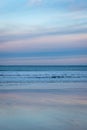 Horizon with waves and brightly coloured sunset reflected in wet, sandy beach, Scotland Royalty Free Stock Photo