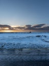 From the horizon Woman on a horse galloping along the shore of the fully snow covered black sand beach of Iceland Royalty Free Stock Photo
