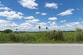 Horizontal asphalt road with grassy pastures and meadow with small village. Royalty Free Stock Photo