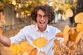 Horizontal autumn shot of happy handsome winner young man with glasses playing with leaves outdoors.Successful male student enjoy Royalty Free Stock Photo