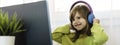 Horizontal banner or header with elementary schooler girl in headphones sitting at desk on laptop - Cute girl studying online from Royalty Free Stock Photo