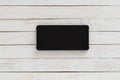 Horizontal black smartphone with dark screen on white wood texture background Royalty Free Stock Photo