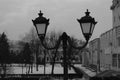 Horizontal black and white photo of an old street lamp in a cityscape with a blurred background on a cloudy winter day. Royalty Free Stock Photo