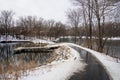 A Horizontal bucolic view of the path on a frozen lake with icy sidewalks and a small wooden boat pier