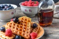 Heart shape gaufre with maple syrup and forest fruits on rustic wooden table