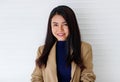 Horizontal close-up portrait shot of an attractive smiling young adult Asian woman in the formal brown suit and blue clothes Royalty Free Stock Photo