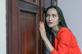 Horizontal close-up portrait of a woman in a red suit eavesdropping, spying on the door of the boss Royalty Free Stock Photo