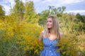 Horizontal closeup portrait of a charming blonde on a background of a blooming field outside the city Royalty Free Stock Photo