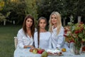 Horizontal closeup portrait of three beautiful women of different generations sitting at a table in their beautiful garden at Royalty Free Stock Photo