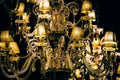 Horizontal closeup shot of an old-styled golden chandelier with a light on a black background