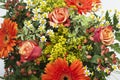 Detail shot of a bouquet of orange, yellow and red flowers in a vase.