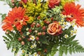 Detail shot of a bouquet of orange, yellow and red flowers in a vase.