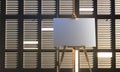 Horizontal Easel With Blank White Canvas On Wooden Jalousie Background. 3D rendering. Empty space. Copy Space