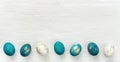 Horizontal Easter banner with colorful eggs painted in turquoise, blue and gold. Easter eggs on white wooden background for loft