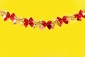 Horizontal festive background: shiny red and gold bows on a yellow background - flat lay. Copy space