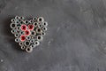 Heart made of pop rivet nuts and locknuts with red plastic, stainless steel mandrel on black tectured chalk board