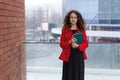 Frontal portrait of a woman, working, real estate agent, making notes on the agenda, over outside, building background.