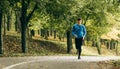 Horizontal full body image of young jogger man jogging outdoor in the forest background. Fitness male exercising in the park, Royalty Free Stock Photo