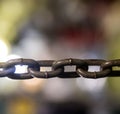 Horizontal gray metal chain large links in close-up tension on background blur