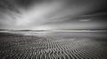 Horizontal greyscale shot of mudflat under the crazy cloudy sky