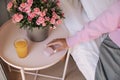 Horizontal image caucasian woman's hand with pink wireless headphones, juice and flower.