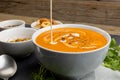 Horizontal image of cream pouring into bowl of tomato soup, with toast and leaves Royalty Free Stock Photo