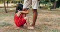 Horizontal image of a daughter spending time with his father swinging on daddy`s leg outdoors. Ã¯Â¿Â½ute little girl playing with her Royalty Free Stock Photo