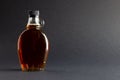 Horizontal image of glass bottle of maple syrup on dark grey background, with copy space Royalty Free Stock Photo