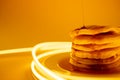 Horizontal image of maple syrup pouring onto stack of pancakes, yellow background and copy space Royalty Free Stock Photo