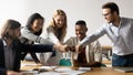 Five multiracial staff members show unity stacked hands in circle