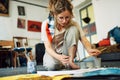 Horizontal image of a pretty female artist sitting on the floor in the art studio and painting on paper with a brush. A woman Royalty Free Stock Photo