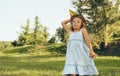 Horizontal image of pretty little girl playing with a paper plane in summer day in park. Cute kid throwing a paper airplane Royalty Free Stock Photo