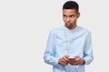 Horizontal image of serious African American young man messaging and blogging on cellphone. Royalty Free Stock Photo
