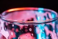 Horizontal image of the top of an empty glass of Champaign, background with red and blue lights