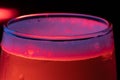 Horizontal image of the top of a full glass of Champaign in the background with red and blue lights