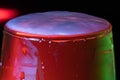 Horizontal image of the top of a full glass of Champaign in the background with red and blue lights