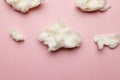 Horizontal image of tufts of homemade white candy floss, on pink background