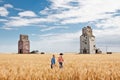 Two cowboy farmers walking in wheat field by elevators. Royalty Free Stock Photo