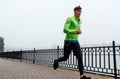 Horizontal image of young athelte man running in the morning on the fog lake background. Fitness male exercising in the park and Royalty Free Stock Photo