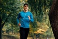 Horizontal image of young jogger man jogging outdoor in the nature background. Fitness male exercising in the park, wearing blue Royalty Free Stock Photo