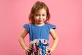 Horizontal isolated shot of four year old girl in beautiful blue dress on pink background. Royalty Free Stock Photo