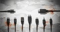 A horizontal line of assorted electronic cables and connectors including USB and audio jacks on a textured gray peeling paint Royalty Free Stock Photo