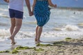 Image of a couple of people strolling on the beach holding hands