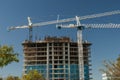 Horizontal mage of White crane towers at a large construction site for a condominium complex