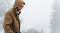Horizontal outdoor image of a young traveler man walking on a foggy day in mountain. Male wearing raincoat and eyeglasses Royalty Free Stock Photo