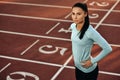 Horizontal outdoor image of young woman athlete posing on racetrack at stadium. Portrait of beautiful professional sportswoman Royalty Free Stock Photo
