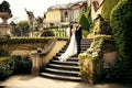 The horizontal outdoor portrait of happy hugging newlyweds standing on the stairs of the beautiful castle. Prague